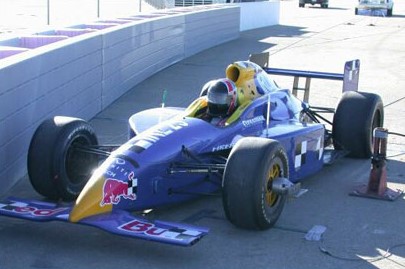 A blue Formula 1 race car parked beside the SAFER Barrier.