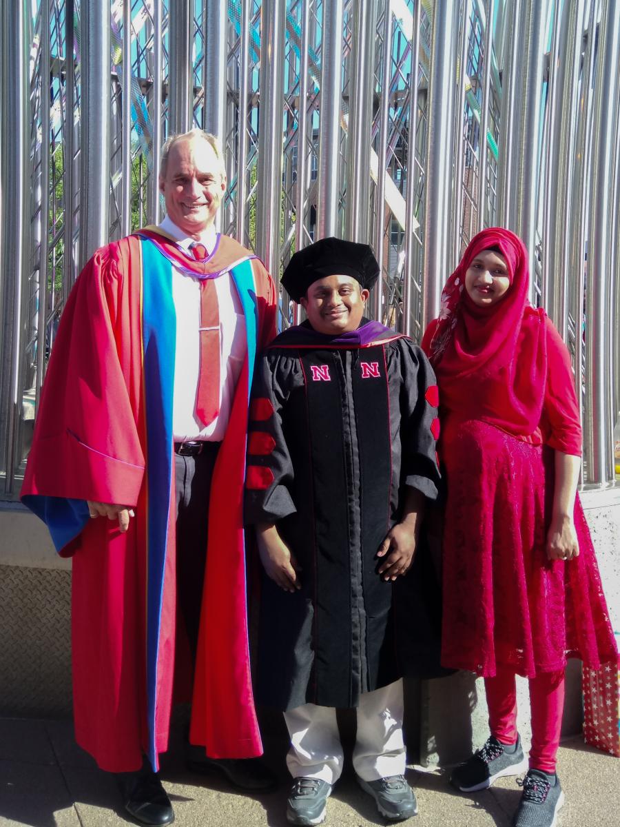 Dr. Laurence Rilett (left) with Mm Shakiul Haque (center) and his wife (right) standing and smiling with graduation gowns