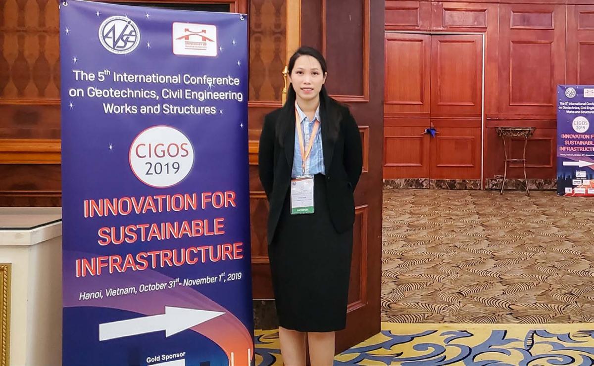 Huong Pham standing next to CIGOS 2019 conference banner.