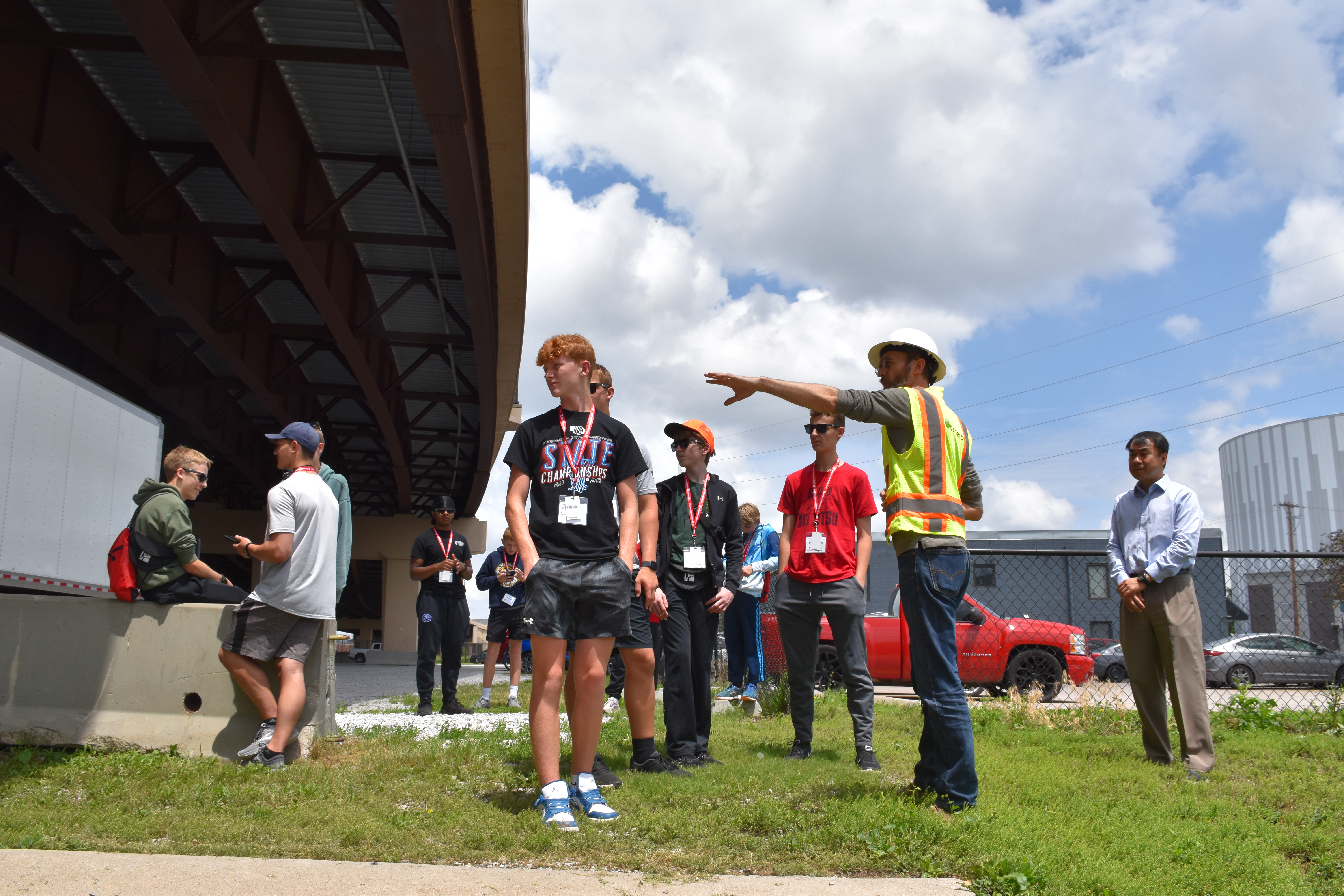 Benesch employee showing a group of high school students the underneath structure of a bridge