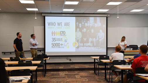 Three engineers from Felsburg Holt and Ullevig standing next to a projector screen.