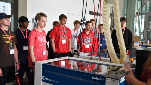 Students viewing a laser cutter machine.
