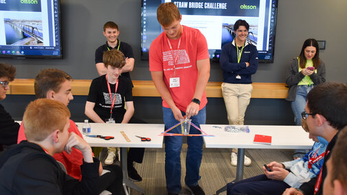 Olsson engineers and students test straw bridges between two tables.