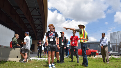 Benesch employee showing a group of high school students the underneath structure of a bridge