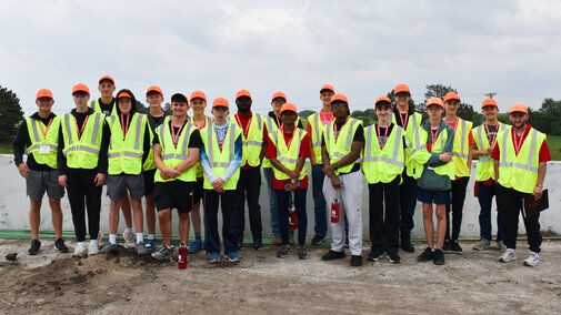 Group photo of all Discover Transportation Engineering students at a highway construction site in saftey vests and hats.