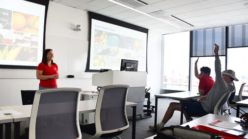 Union Pacific representative stand at the front of a classroom with seated students raising their hands.