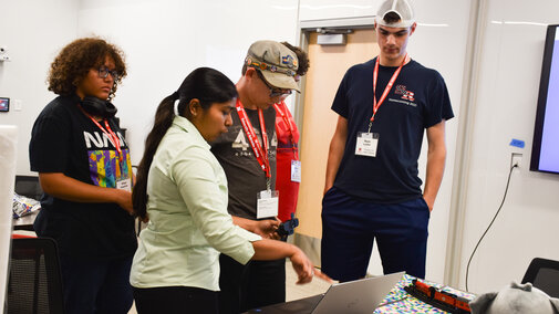 Graduate student showing how 3D modeling works on a laptop to students.