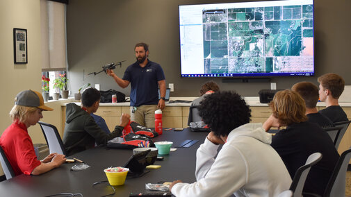 Engineer holding a drone presenting to students in a conference room at Felsburg Holt & Ullevig.