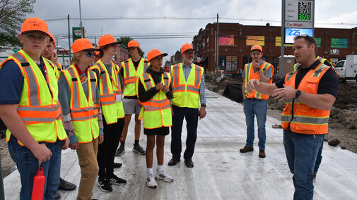 Students standing on a road during a tour of a construction site.
