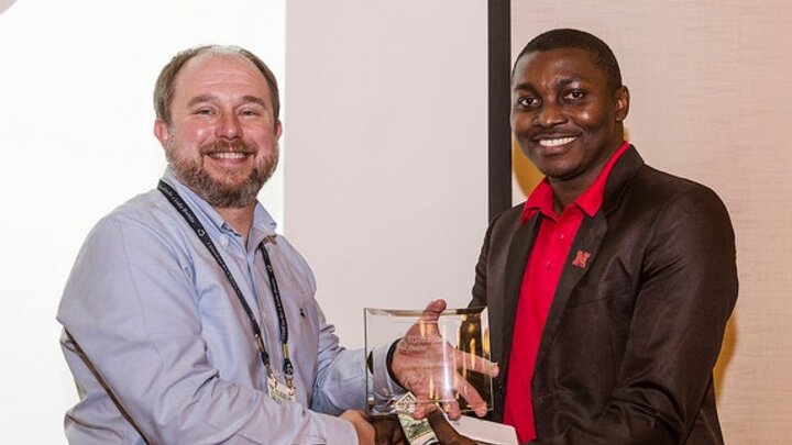 Ronald Barnes and Ernest Tufuor shaking hands and holding award