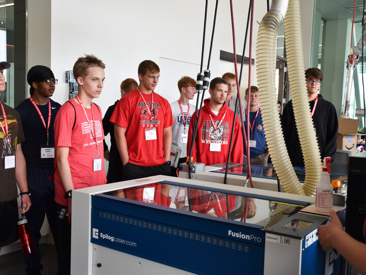 Students viewing a laser cutter machine.