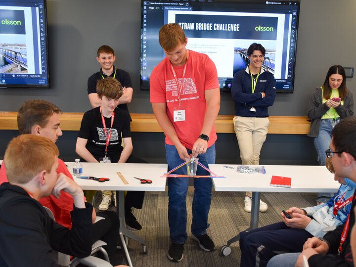 Olsson engineers and students test straw bridges between two tables.