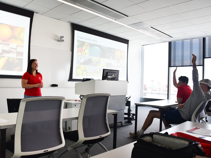 Union Pacific representative stand at the front of a classroom with seated students raising their hands.