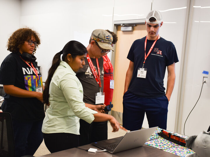 Graduate student showing how 3D modeling works on a laptop to students.