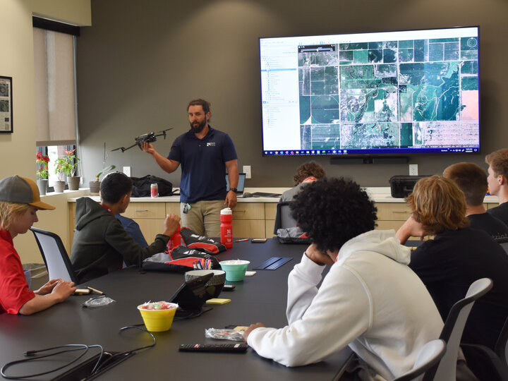Engineer holding a drone presenting to students in a conference room at Felsburg Holt & Ullevig.