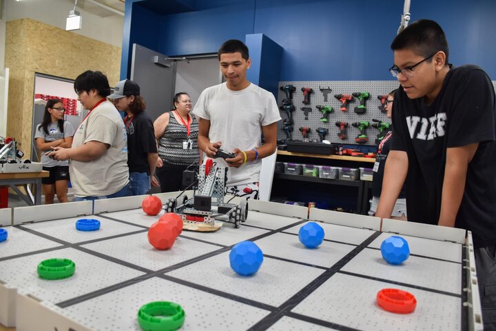 Students control modified robots to pick up spheres and place them into rings.